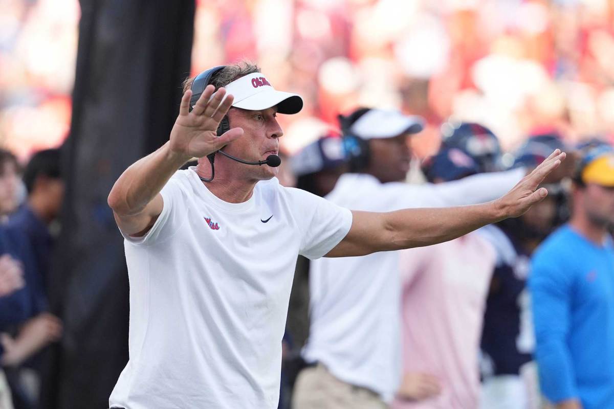 Lane Kiffin with his arms outstretched on the sideline of a football field