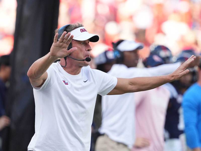 Lane Kiffin with his arms outstretched on the sideline of a football field