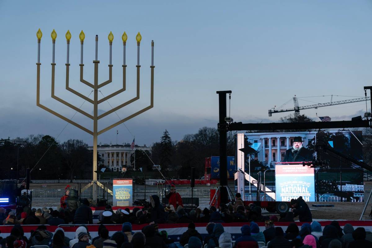 A stage outside with a large Menorah display, the White House visible in the background.