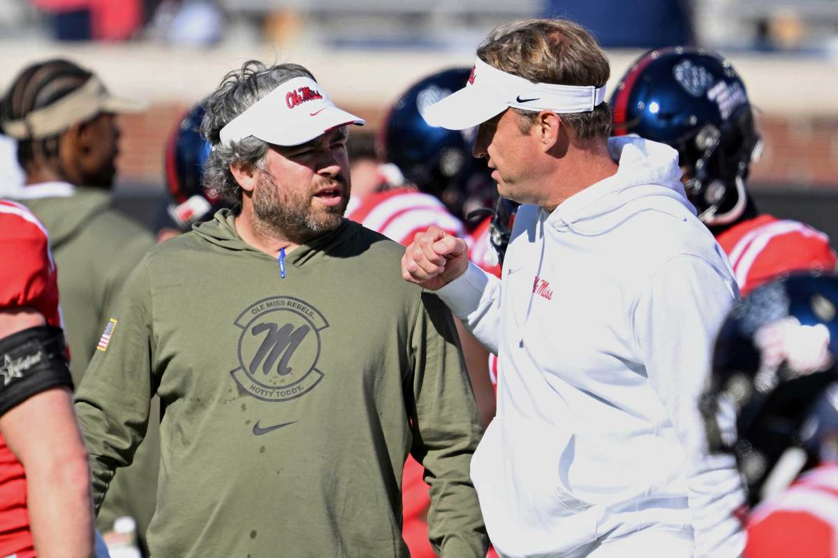 Pete Golding and Lane Kiffin speaking on the sideline during a football game.