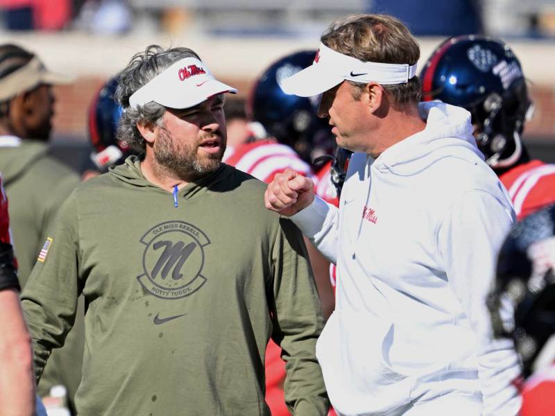 Pete Golding and Lane Kiffin speaking on the sideline during a football game.