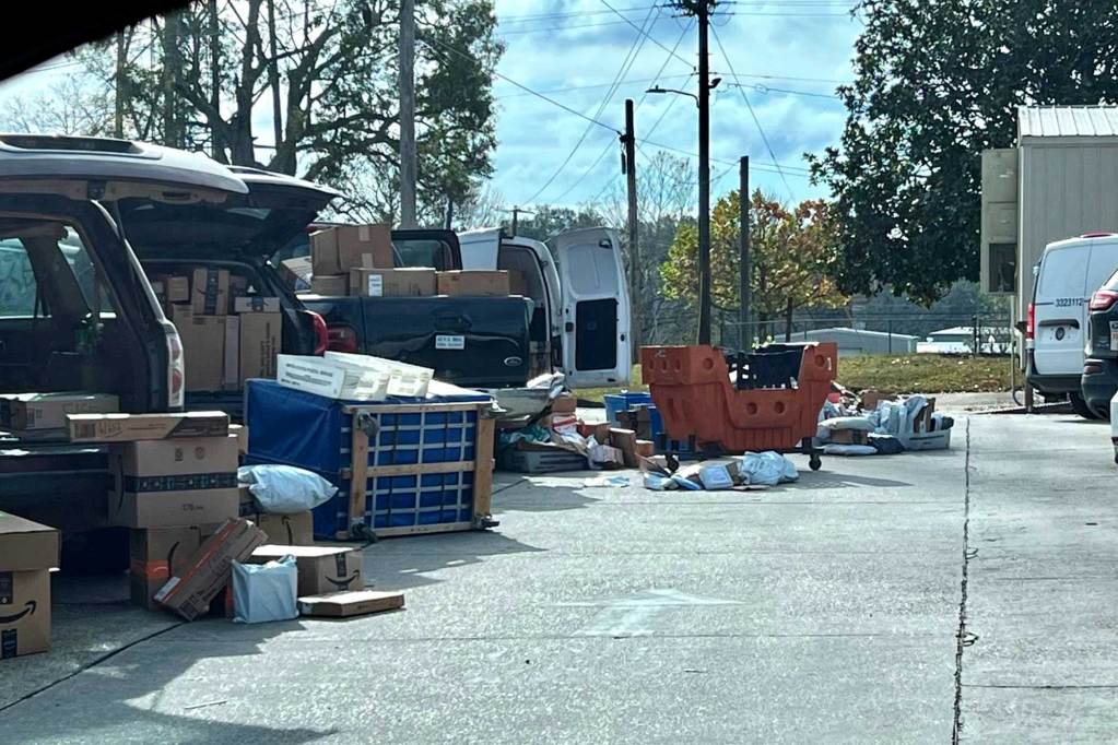 Dozens of packages are scattered across the ground and are packed into the open vehicles.