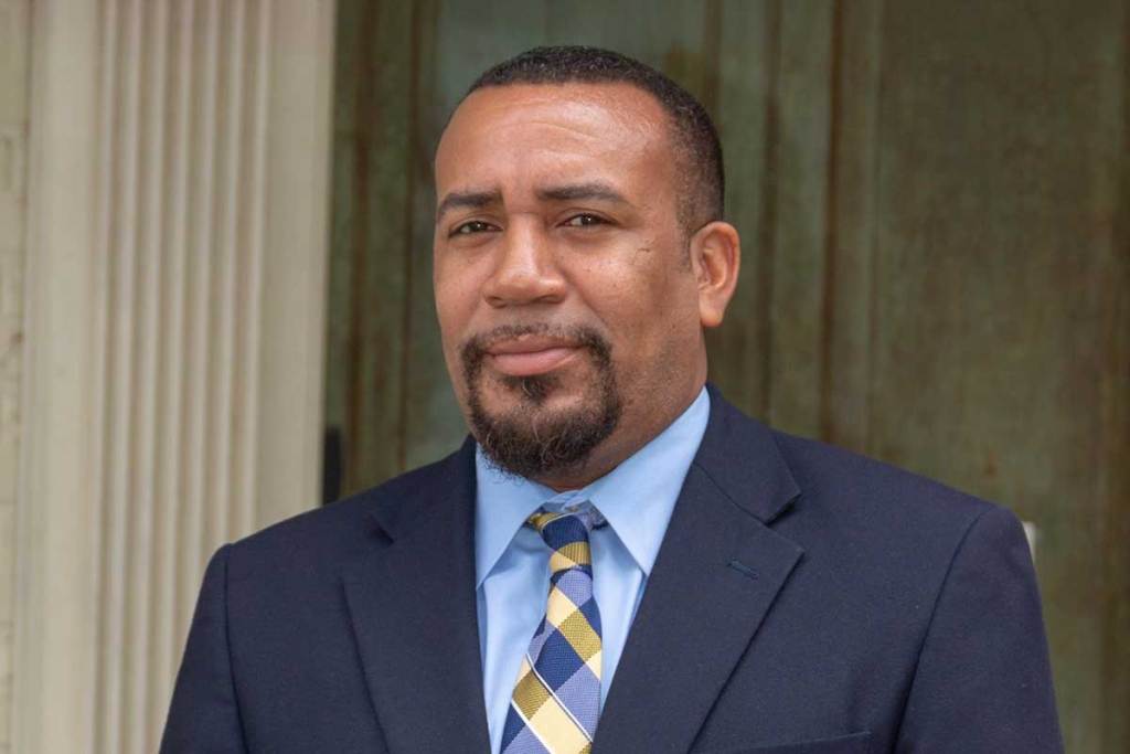 Rep. Jeffery Harness, in a blue suit, stands outside of a building
