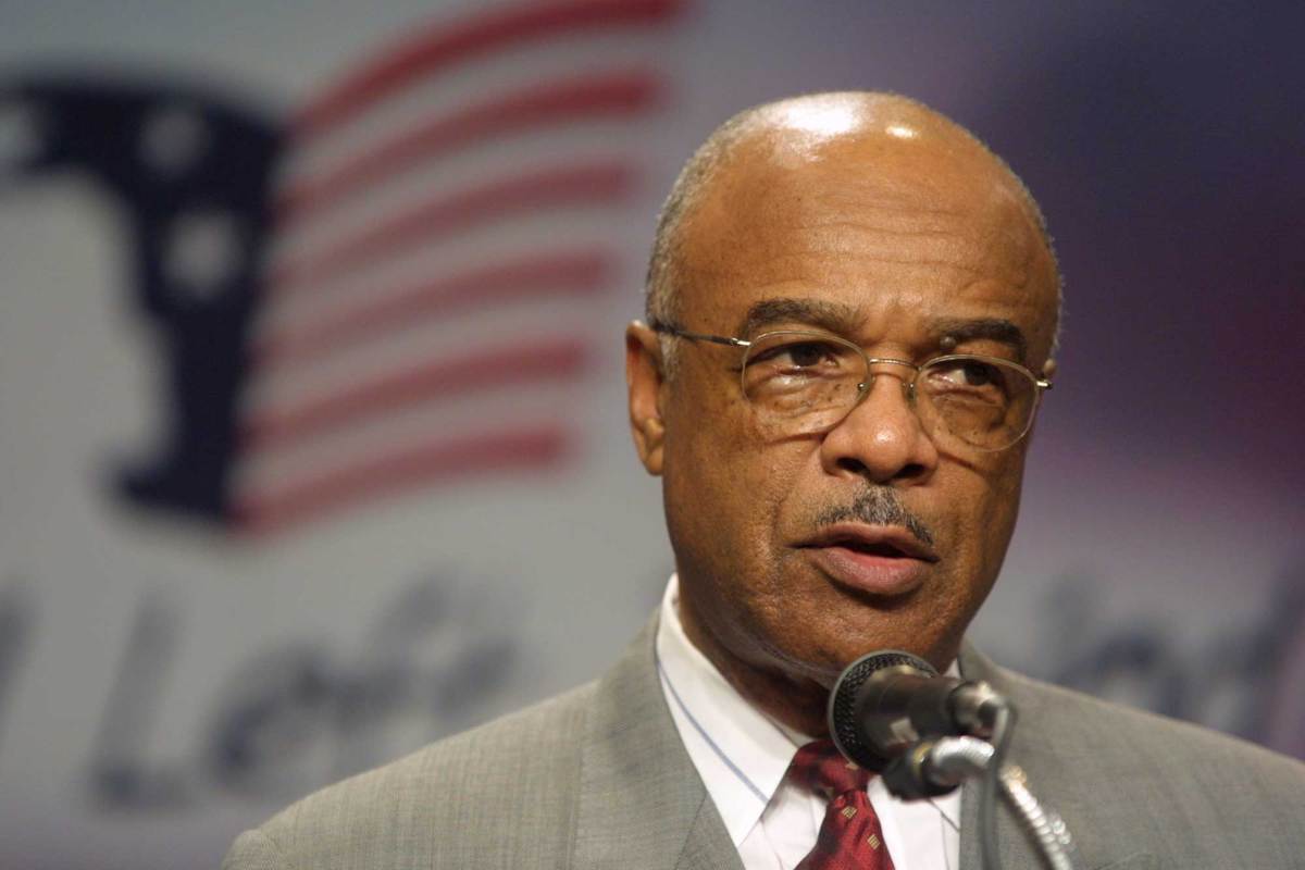 A close-up photo of Rod Paige speaking in front of a No Child Left Behind sign