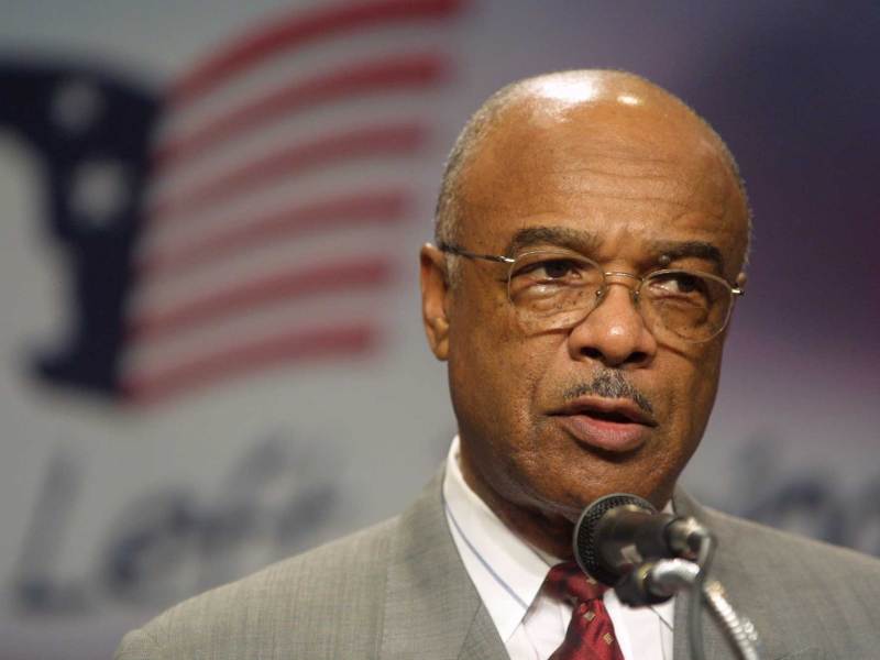 A close-up photo of Rod Paige speaking in front of a No Child Left Behind sign