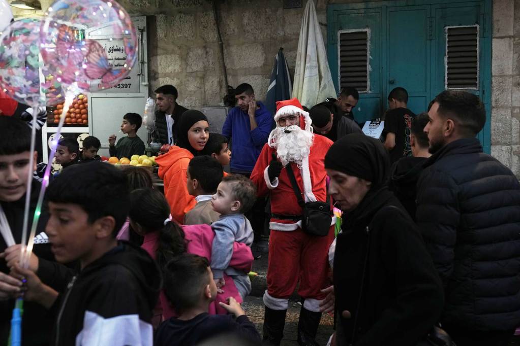 Santa Clause stands outside among a crowd of holiday visitors