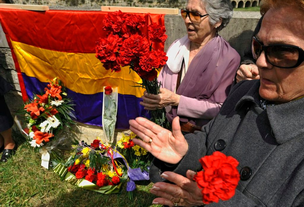 Two women at a memorial with the Spanish flag.