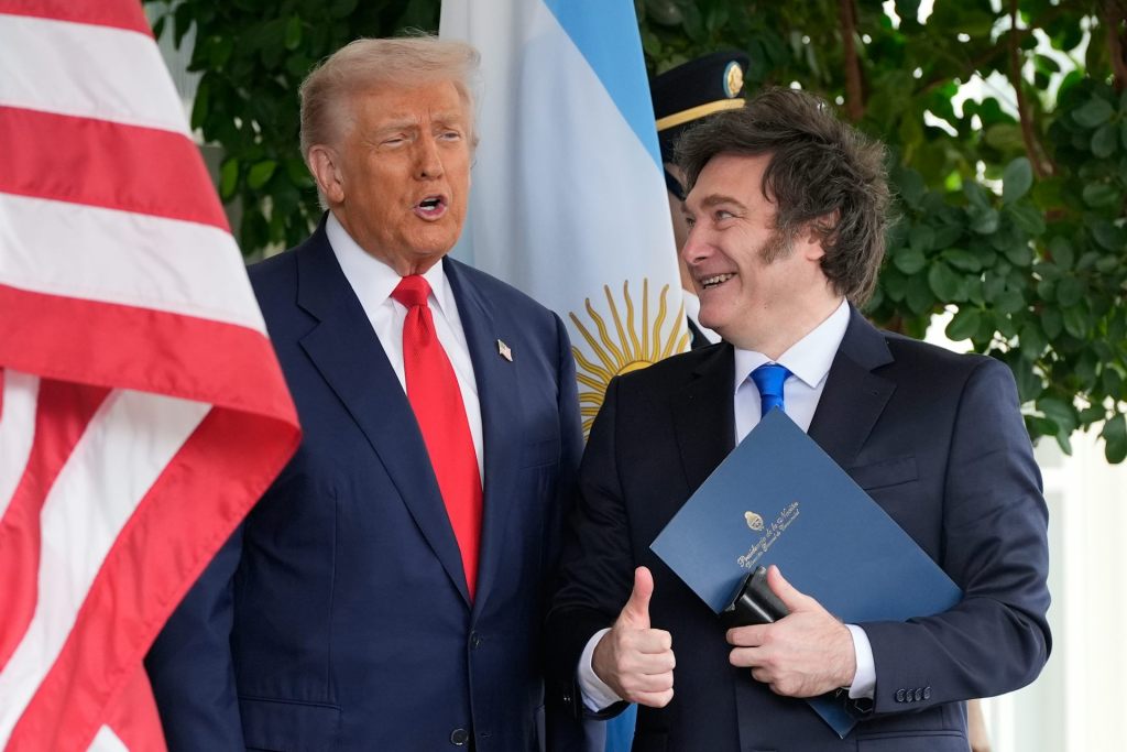 U.S. President Donald Trump with Argentinian President Javier Milei stand side by side outside by their country flags