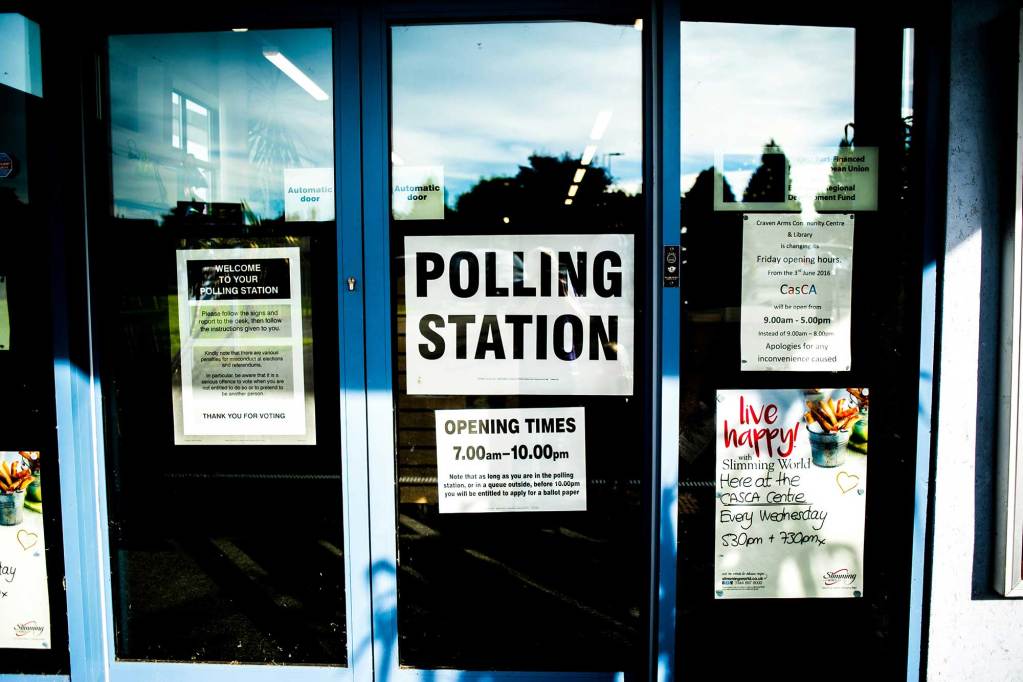 Glass windows on a building with signs indicating the area is a polling station