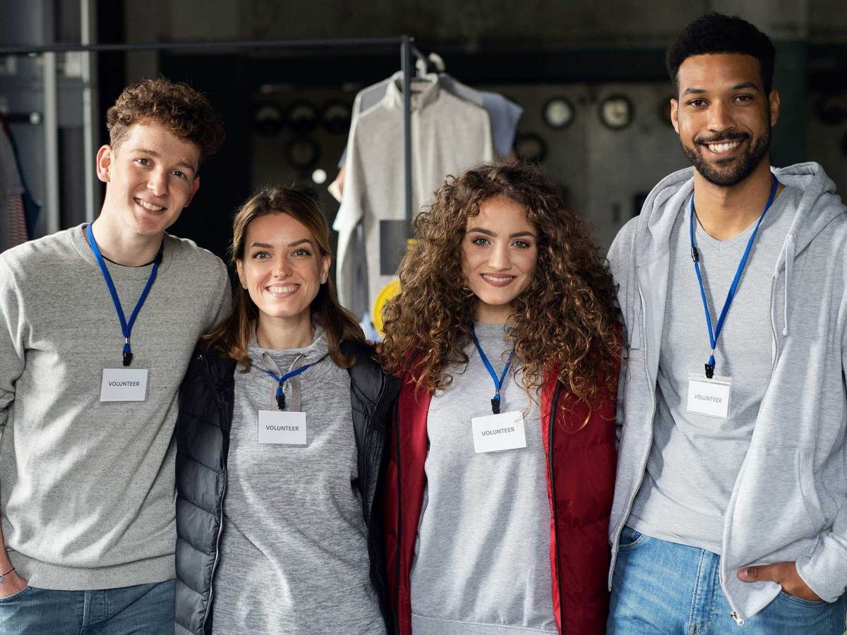 Two men and two women with lanyards around their necks that say ‘Volunteer’ posing for a photo