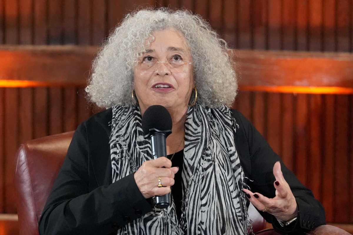 Angela Davis, in black with a zebra print scarf, speaks to an audience