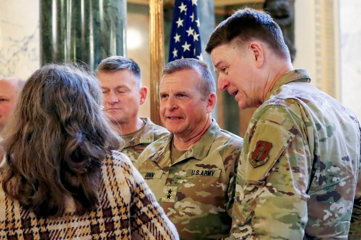Men in army fatigues talk to others in the capitol