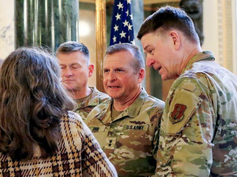 Men in army fatigues talk to others in the capitol