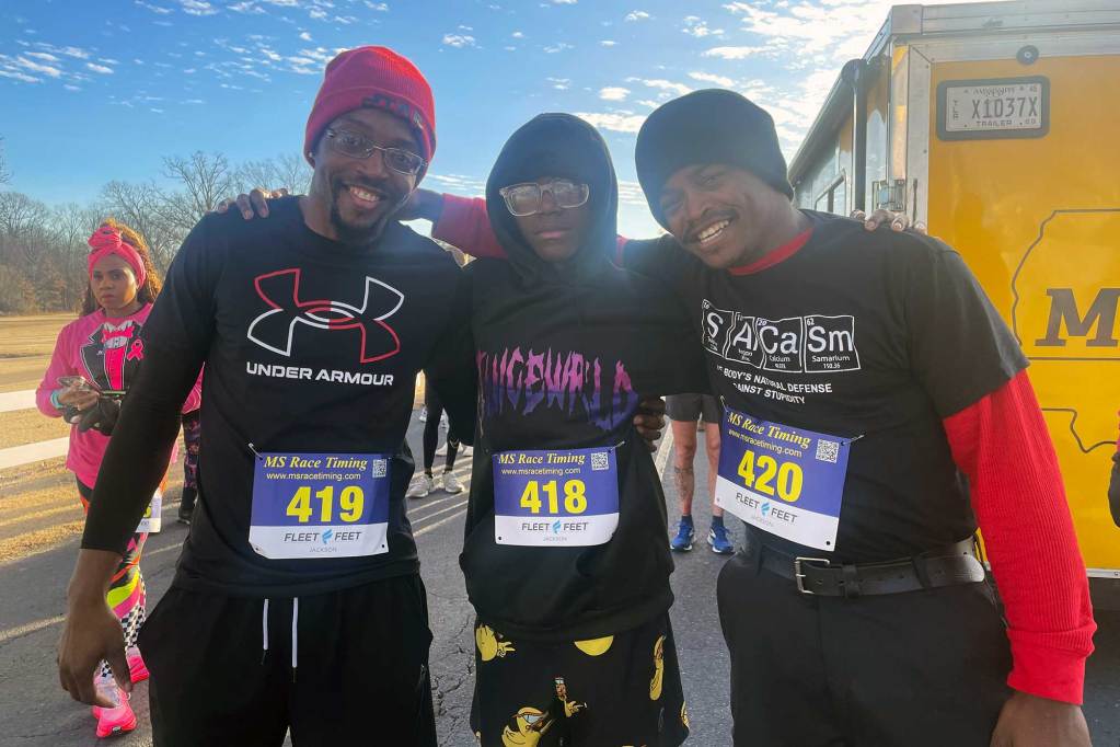 Three runners pose together for a photo. Their numbers are 419. 418, and 420