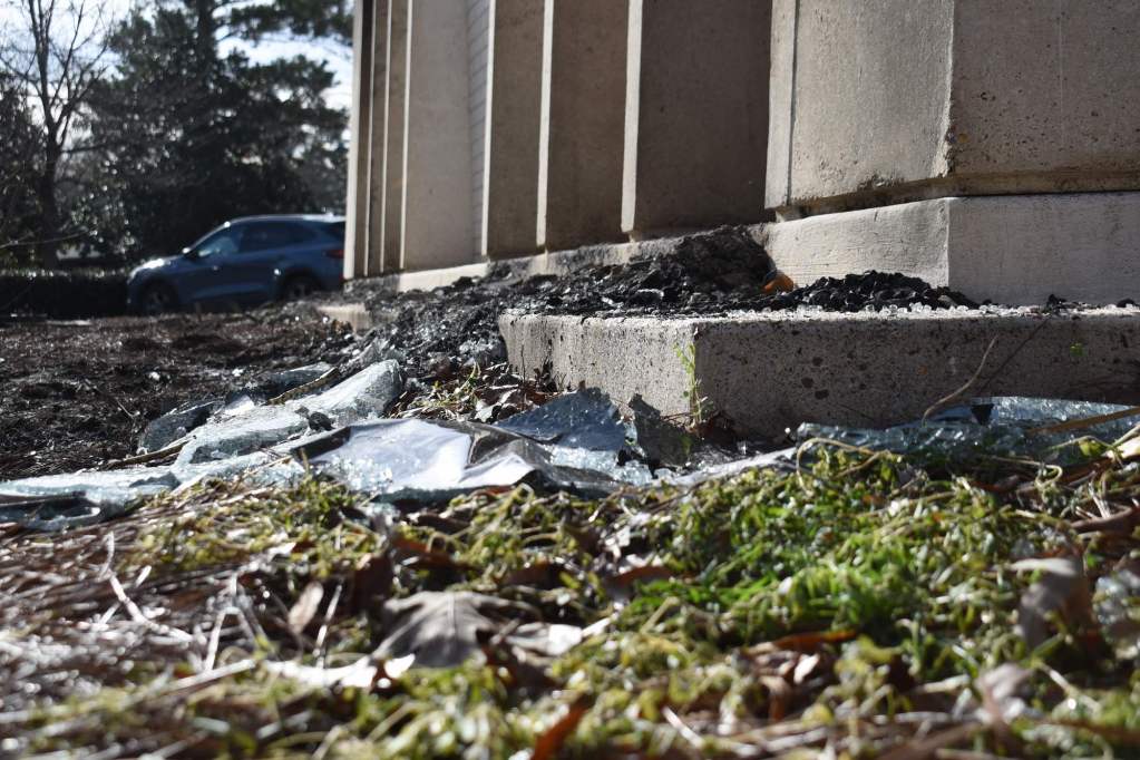 A closeup of shattered class and fire debris outside of a building