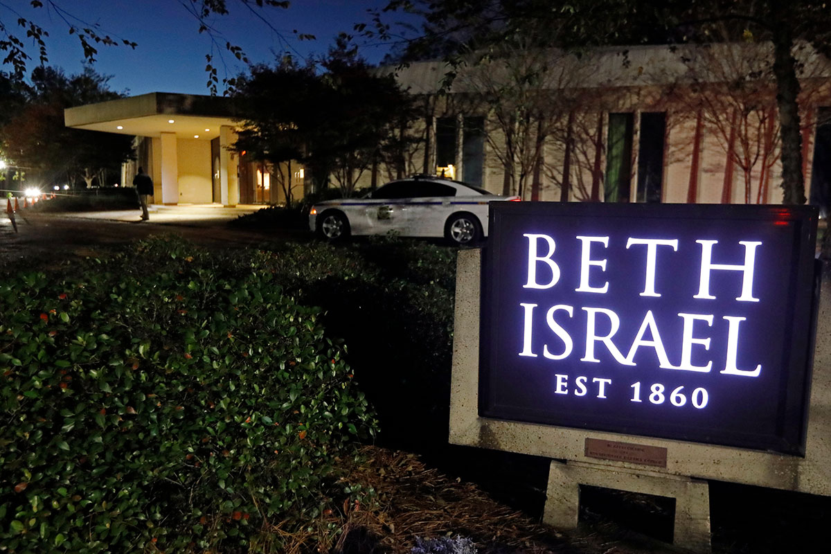 The exterior of Beth Israel synagogue, with a sign saying it was established in 1860, with a local police car parked in front