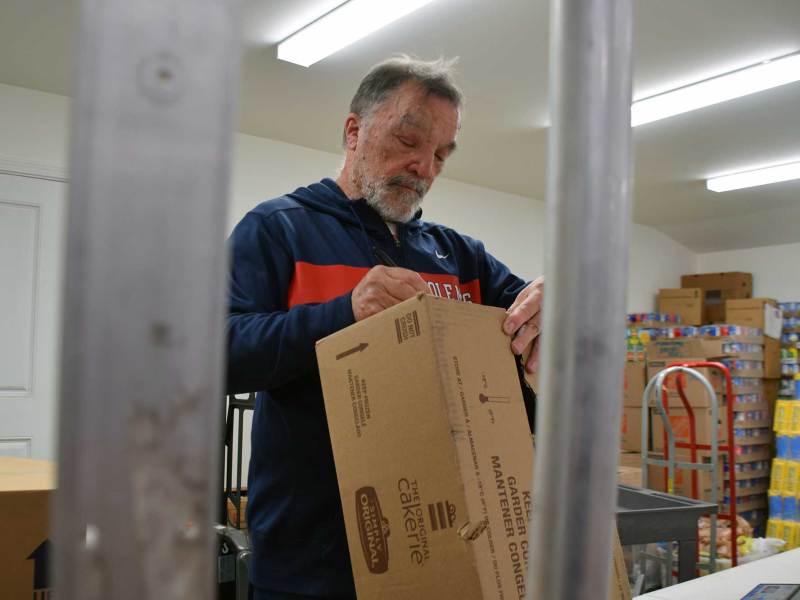 A man weighing boxes inside a pantry inventory room