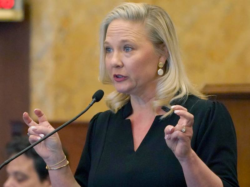 Celeste Hurst speaking at the mic, making air quotes with her hands