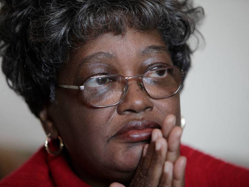 A close-up photo of a woman wearing glasses and a red shirt.