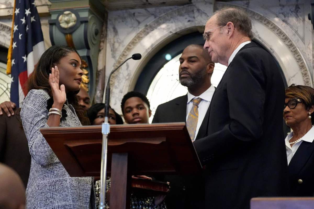 Kamesha Mumford holds one hand up and swears in with Delbert Hosemann officiating opposite of her