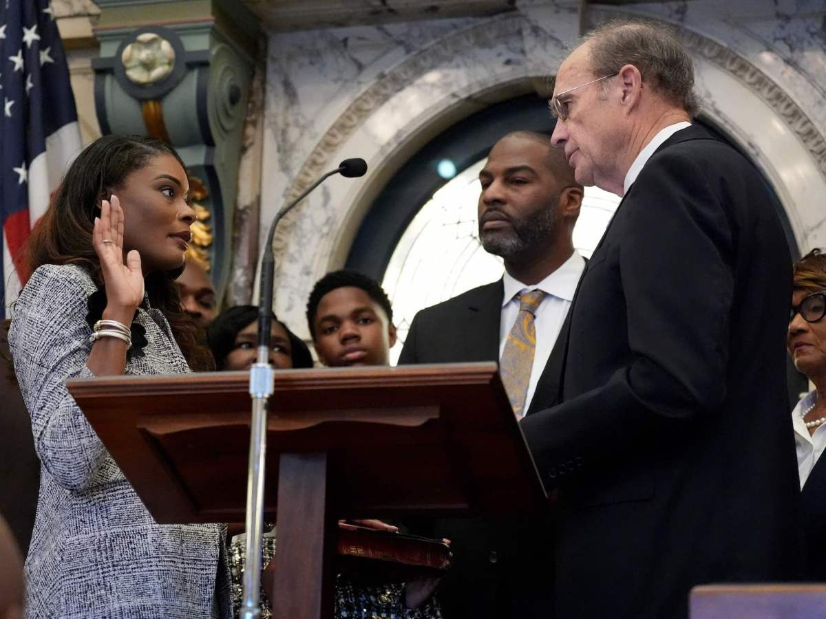 Kamesha Mumford holds one hand up and swears in with Delbert Hosemann officiating opposite of her