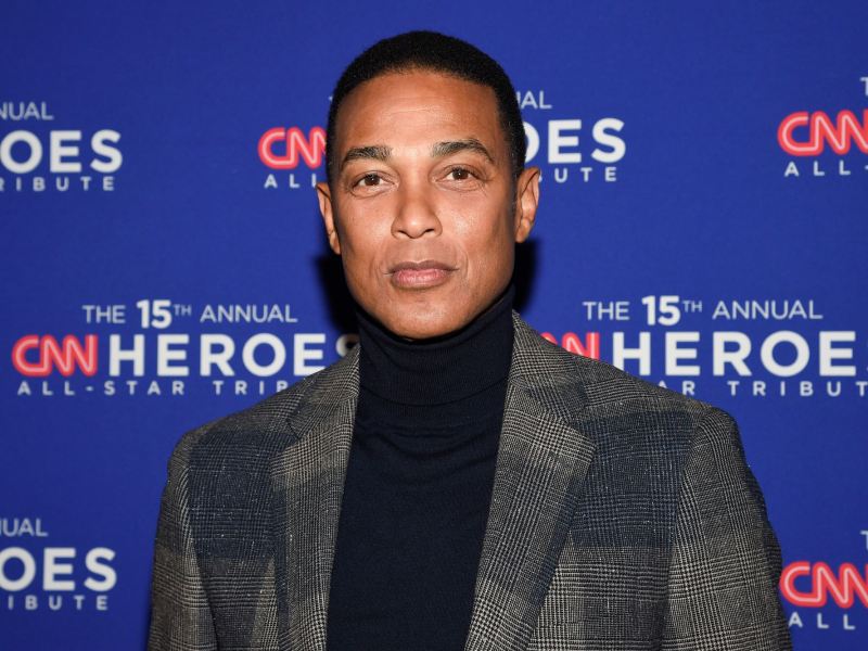 Don Lemon standing in front of a blue wall covered in logos for 'The 15th Annual CNN Heroes All-Star Tribute'