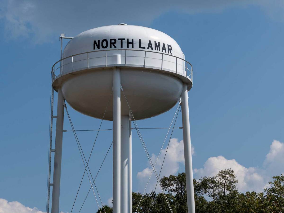 A water tower stands next to the North Lamar Water Association office building.