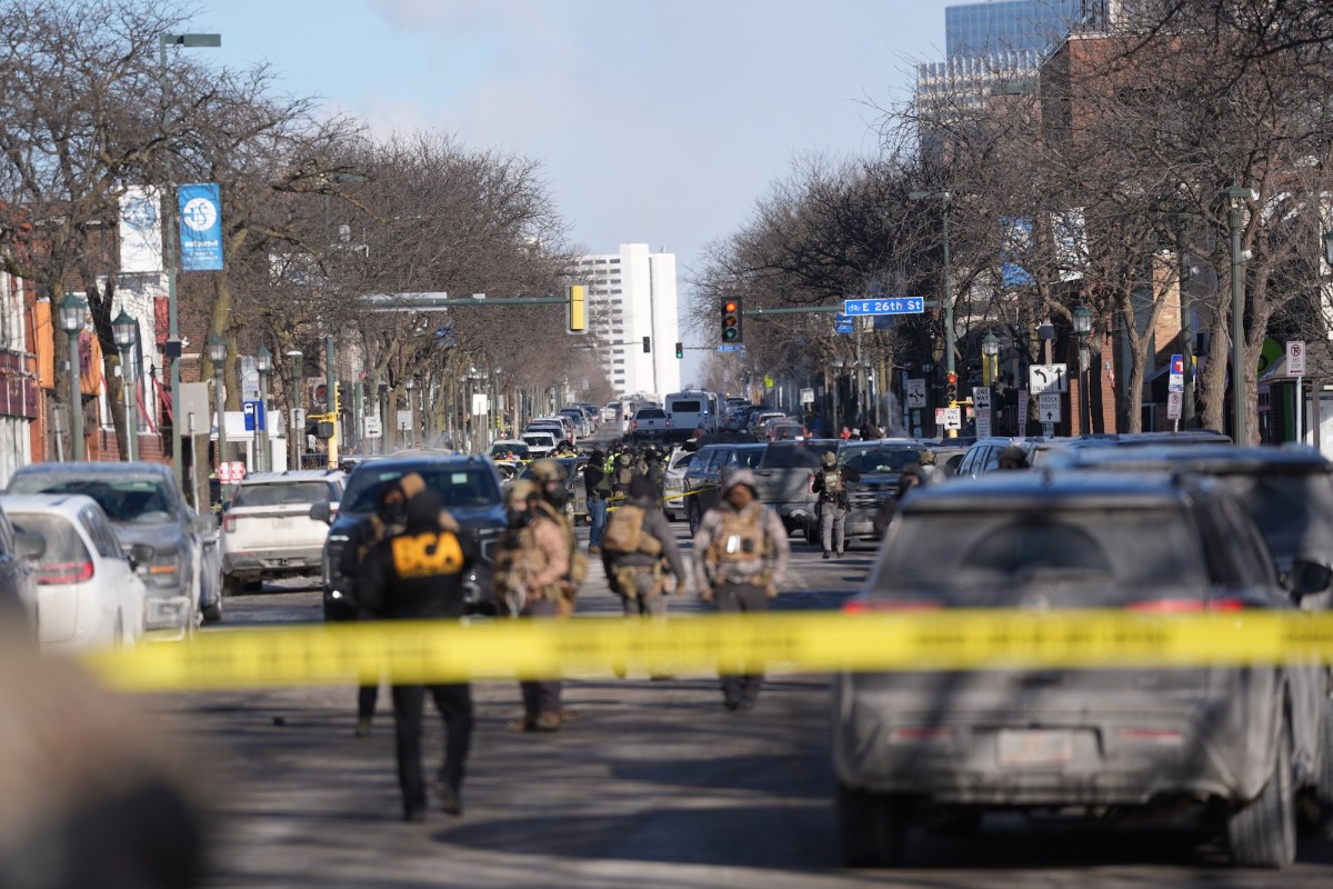 ICE agents standing in a street behind yellow crime tape