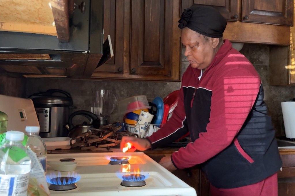 A woman lights all the the burners on her stove in effort to warm her house during a winter storm power outage