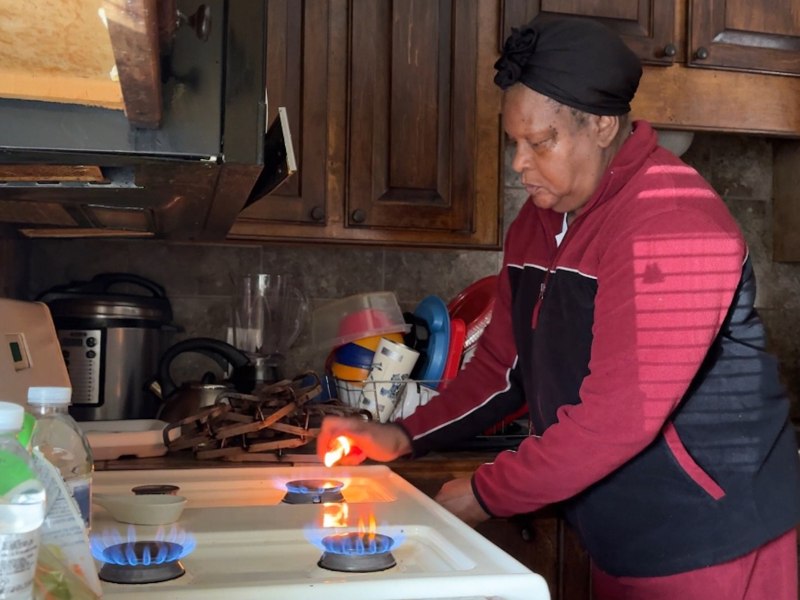 A woman lights all the the burners on her stove in effort to warm her house during a winter storm power outage