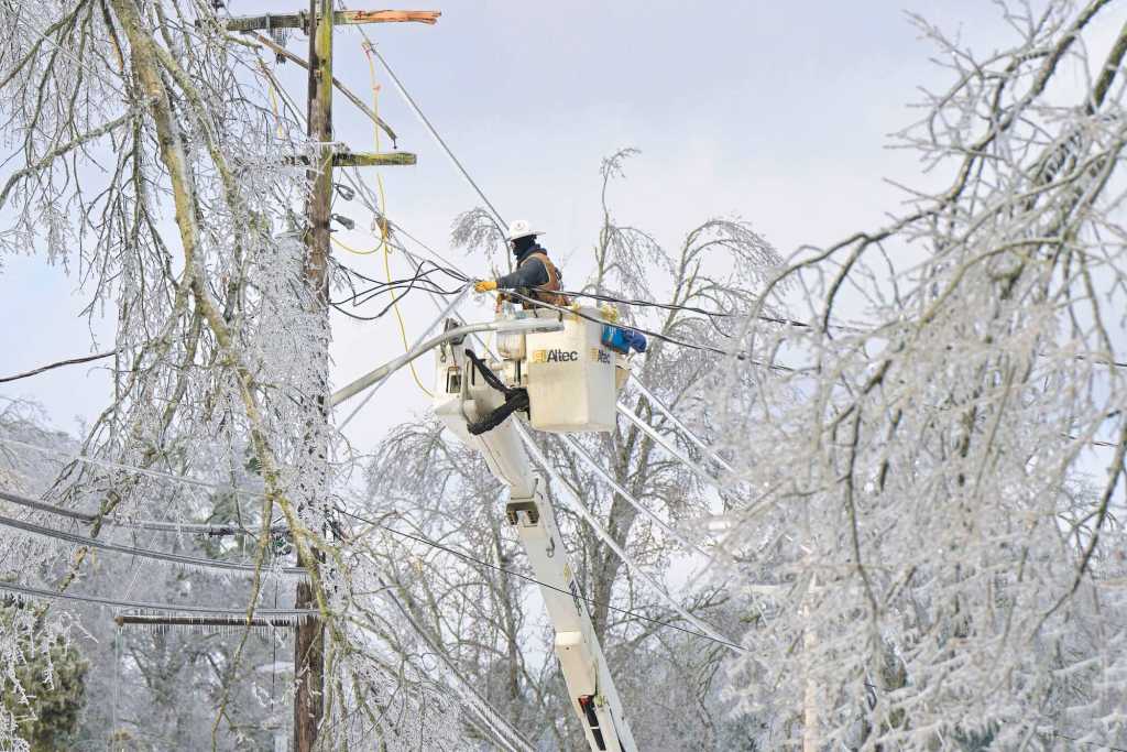 A lineman in a bucket works on icy lines