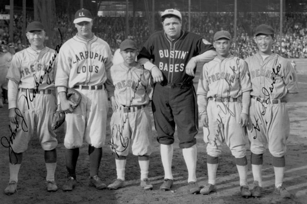 A black and white photograph of six baseball players – four Asian Americans and two white Americans – posing on a diamond while wearing baseball uniforms.