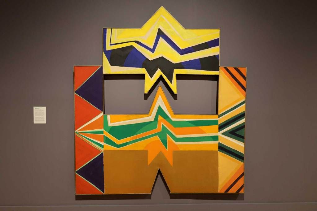 A warm toned painting made of geometric lines and painted on a geometric canvas