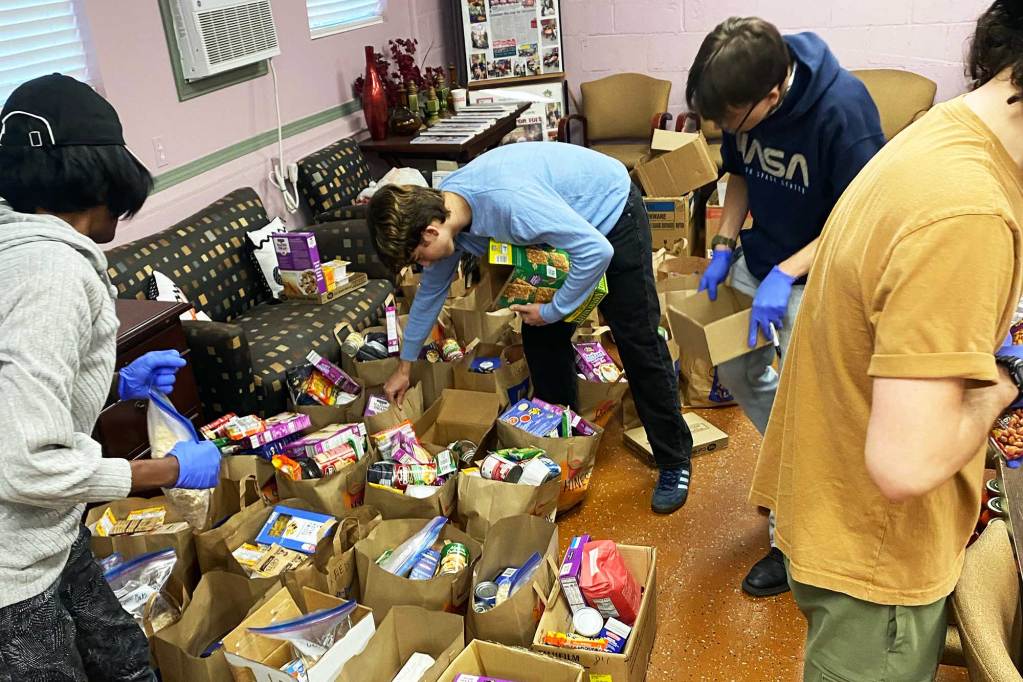 Four people sort through boxes and bags of donated food items