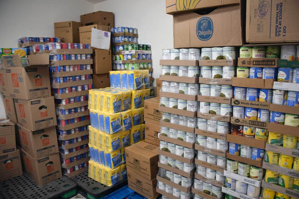 Multiple pallets of canned food line the walls in a pantry inventory room