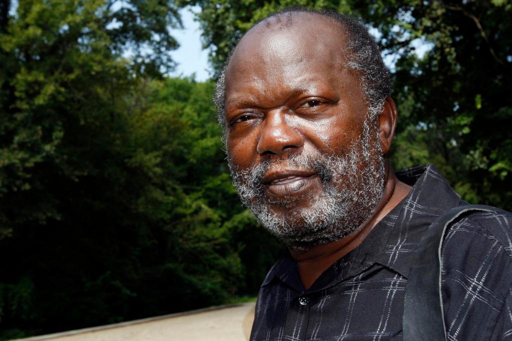 A man smiles for a photo outside