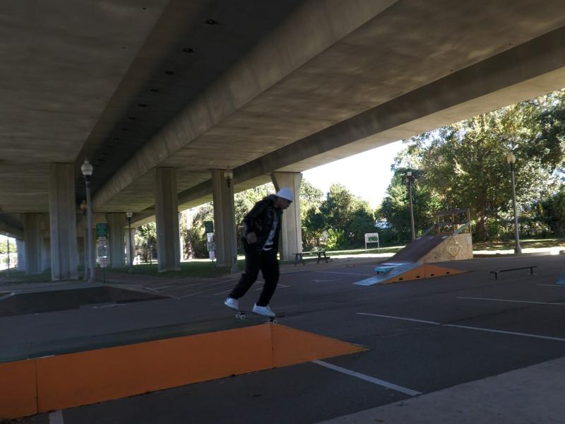 A person on a skateboard rides along a painted ledge at a DIY skatepark located under a concrete overpass in Biloxi, Mississippi.