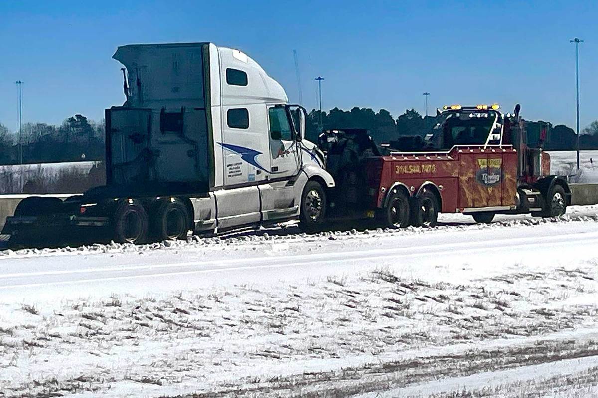 A tow truck seen pulling an 18-wheeler cab through the snow