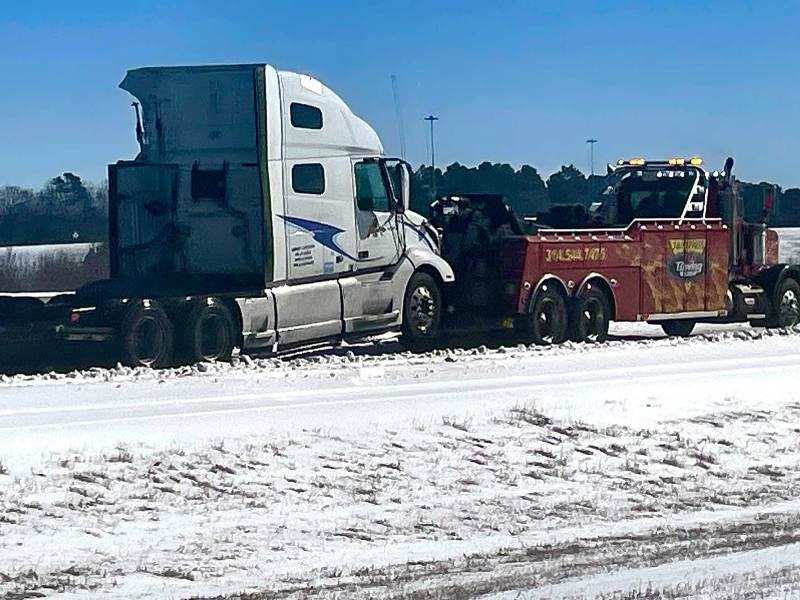 A tow truck seen pulling an 18-wheeler cab through the snow