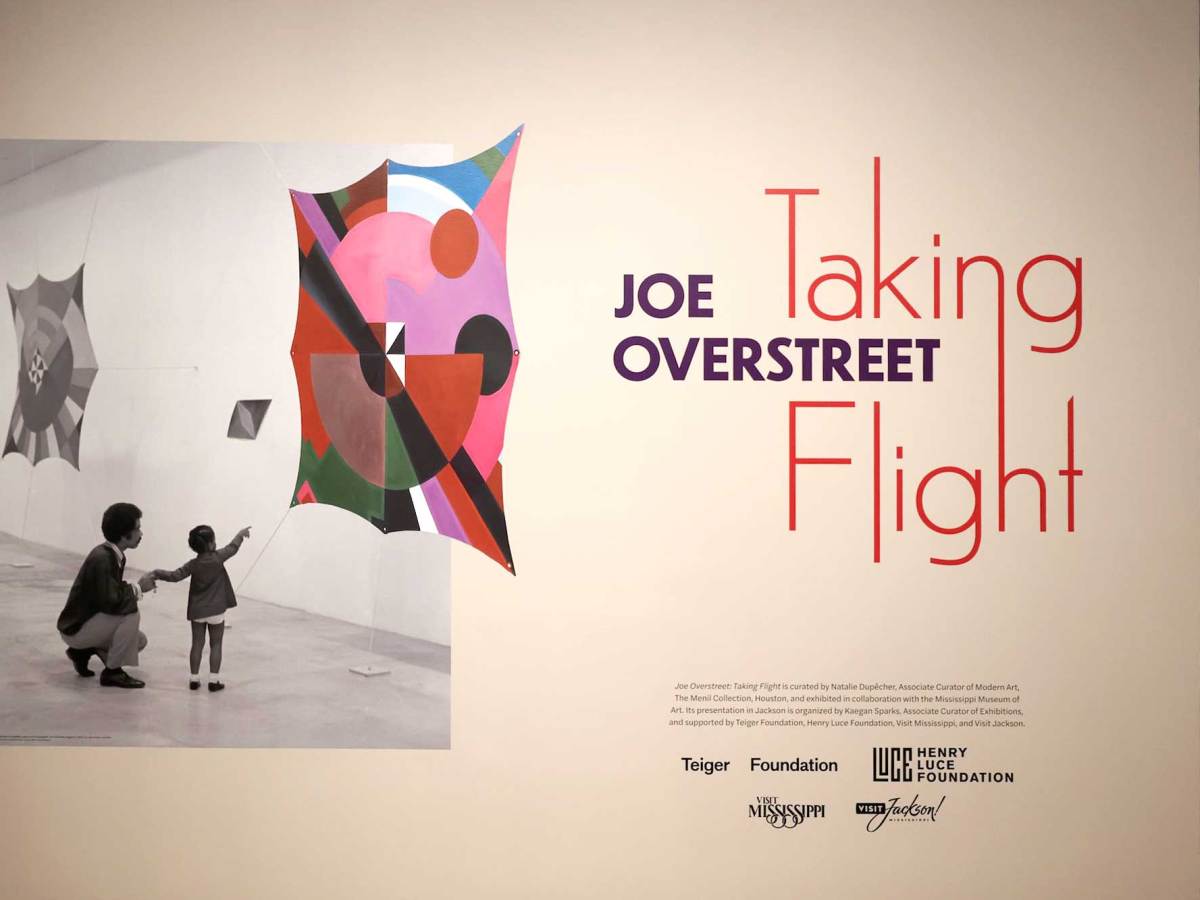 A sign that reads 'Joe Overstreet - Taking Flight'. An image of a Man and little girl pointing at colorful artwork is seen on the left hand side