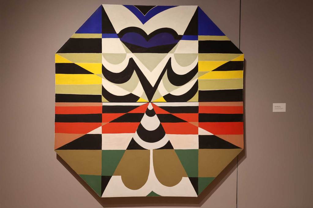 A colorful geometric painting on a hexagon shaped canvas