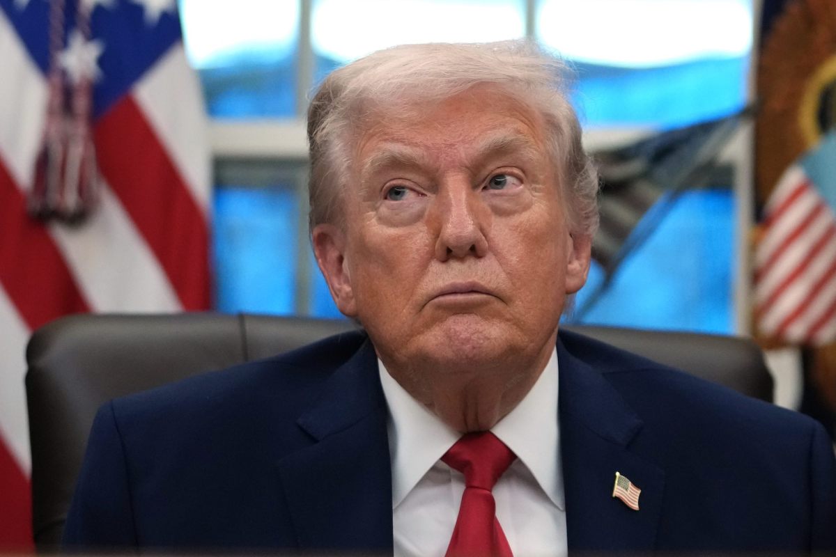 President Trump seated in the Oval Office, listening