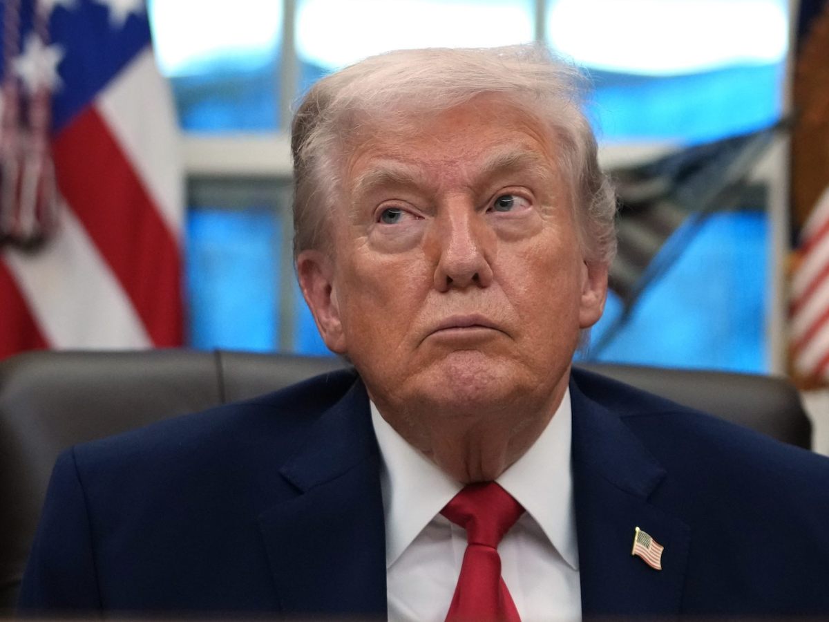 President Trump seated in the Oval Office, listening