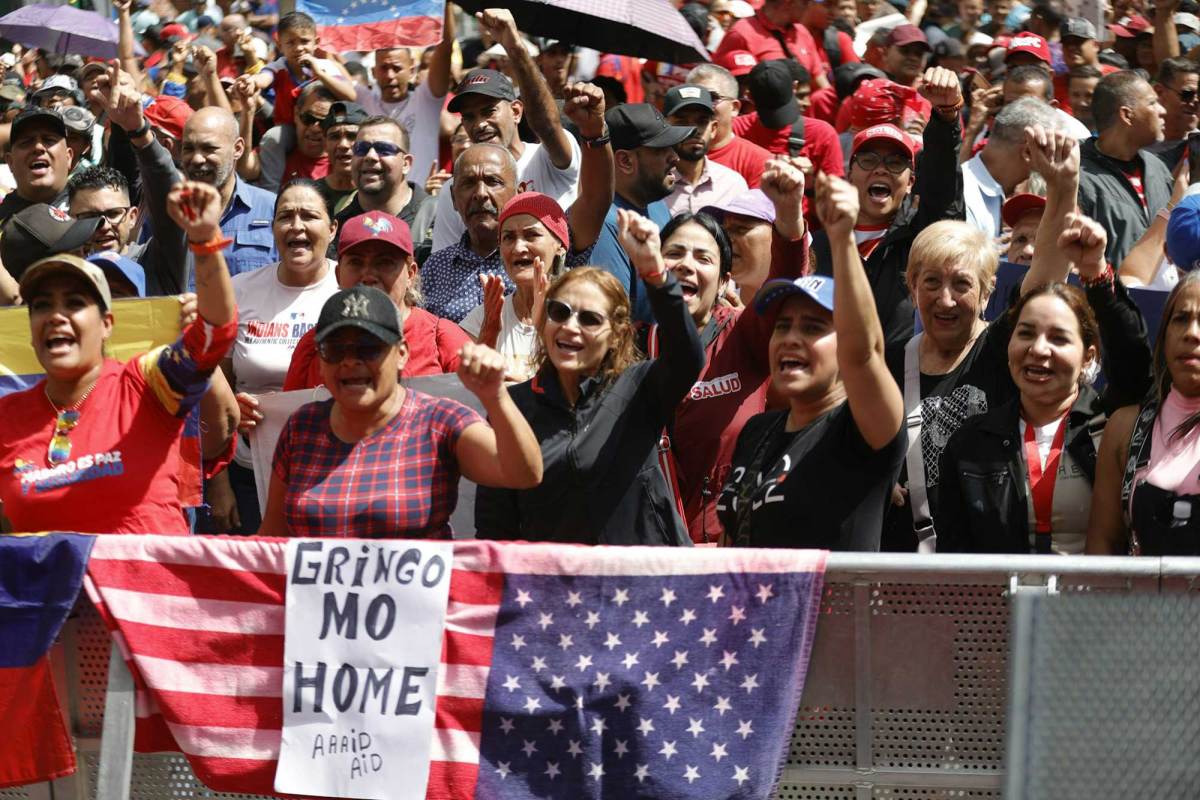 A group of protestors with their hands in the air. A sign reads ‘Gringo Mo Home’