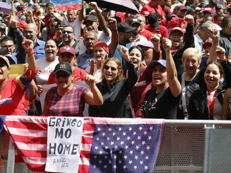 A group of protestors with their hands in the air. A sign reads ‘Gringo Mo Home’