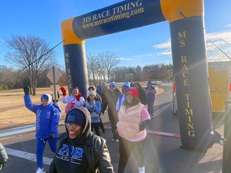Run participants walk through a race marker