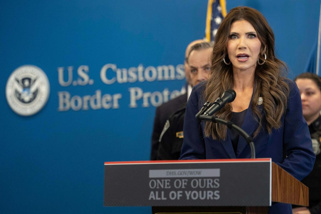 Kristi Noem, the Homeland Security secretary, stands behind a podium at a news conference.