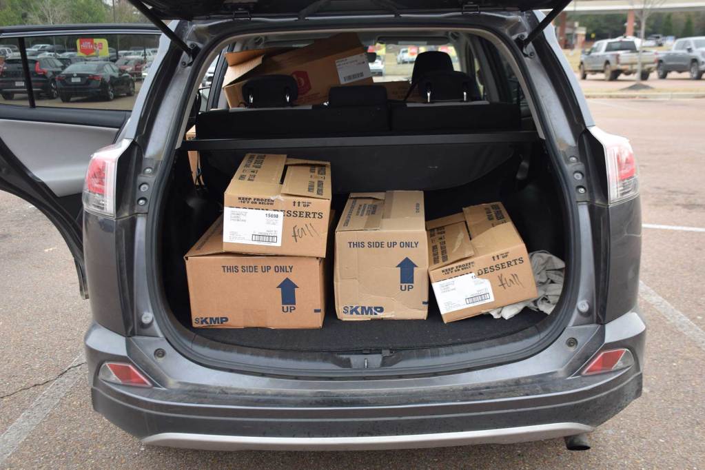 A view into an open trunk of a grey vehicle with boxes in the back.