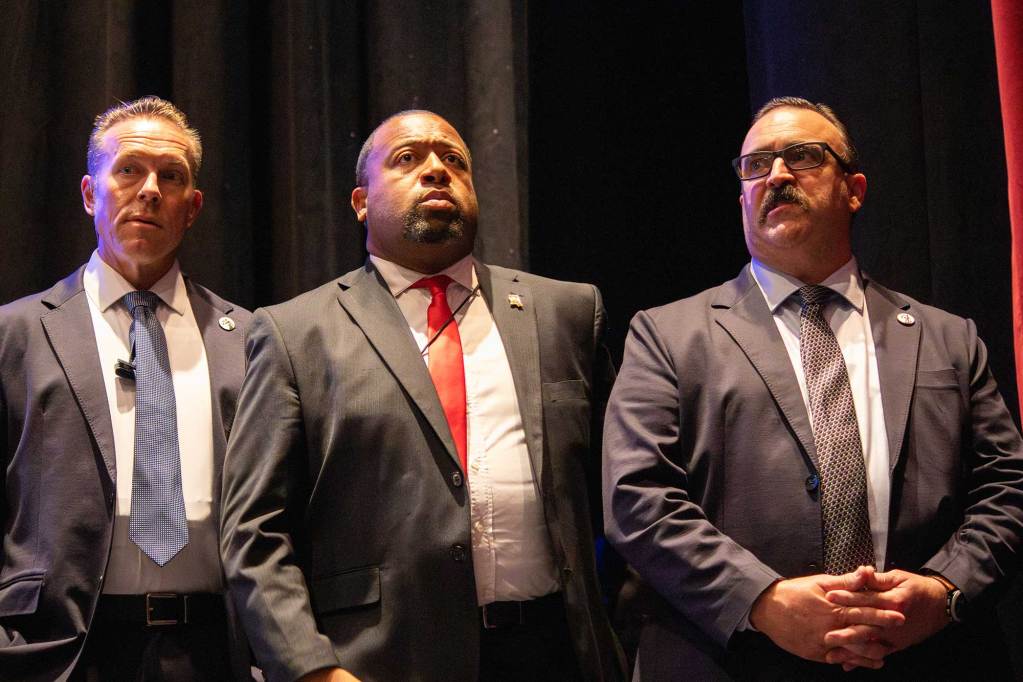 Three men in suits stand off to the suit
