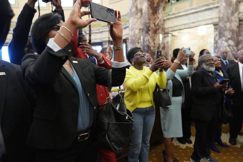 A row of people hold up cameras to record several swearing-ins inside the senate chambers